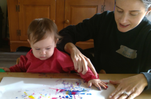 Infant finger painting with educator