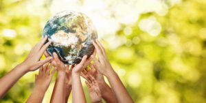 Group of children's hands holding planet earth over defocused nature background