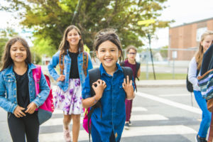 Young girls with backpacks crossing the street near school
