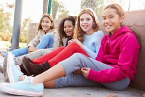 Four young girls sitting on the ground together at a park