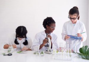 Group of diverse young scientist girls studying science and experimenting with chemicals at laboratory. Research and development concept.