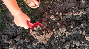 a kids hand using a shovel in dirt