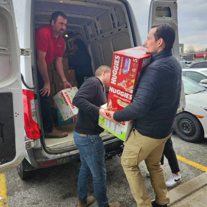 4 3 men unloading boxes of diapers from the back of a van