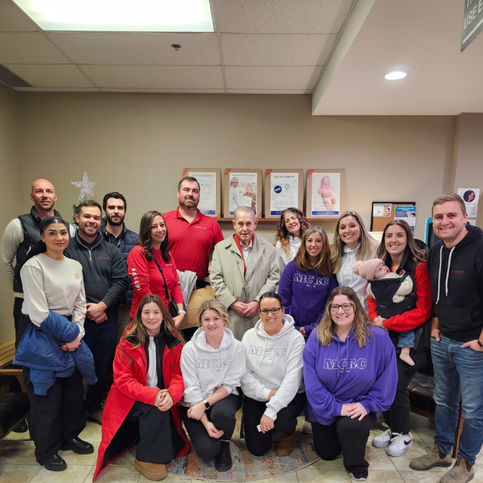 5 a large group of smiling people pose for a photo in the lobby of MCRC