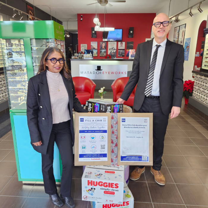 Thursday Jan 2nd (4) 2 people smiling inside of Matador Eyeworks next to a pile of diaper donations for the Infant Food Bank
