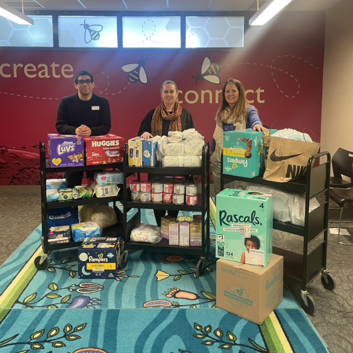 Thursday Jan 2nd 3 people smiling behind 3 carts full of donations of diapers, baby food and formula