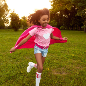 girl running outside with a cape on