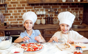 two kids making pizzas