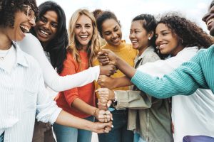 Multicultural group of women stacking hands together - 