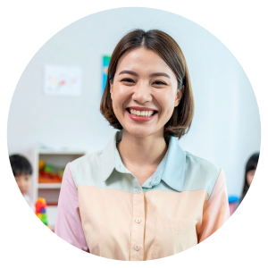 A photo of a young female teacher smiling at the camera in a classroom setting