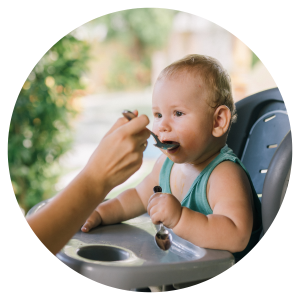photo of a baby sitting in a high chair being fed with a spoon