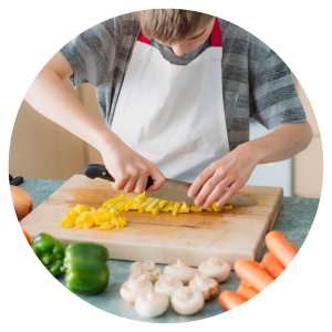 a child wearing an apron and chopping vegetables