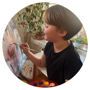 a young child smiling as they paint on a canvas