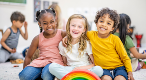 three kids sitting together smiling