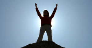 girl standing on mountain with arms in air